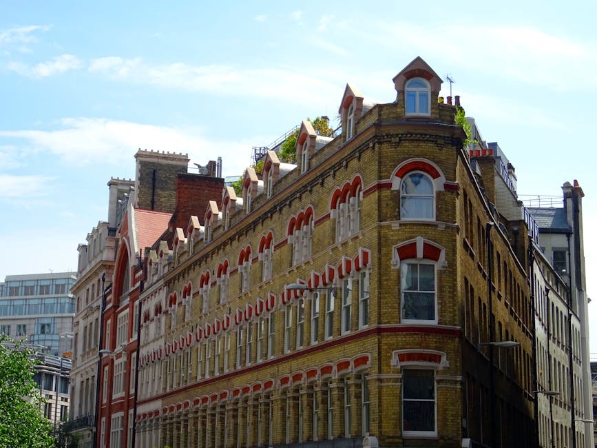 A detailed view of a rooftop terrace garden arranged with a variety of plants, including lush green grass, neatly trimmed hedges, and potted flowering plants, set against a backdrop of urban rooftops.